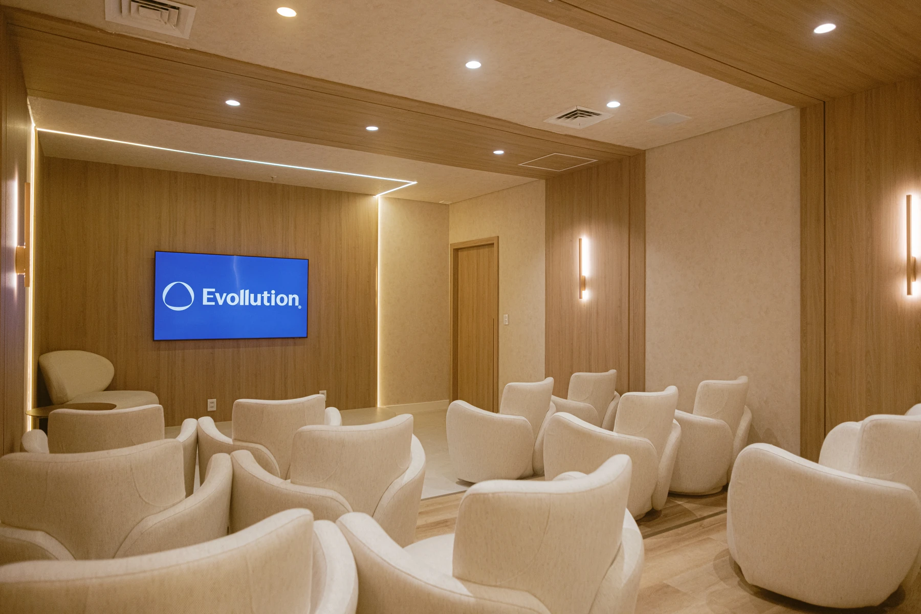 Ambiente do Instituto Evollution com poltronas claras e tela com a marca Evollution